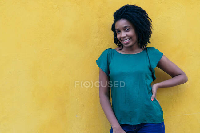 Junge Frau in grüner Bluse steht auf der Straße und lächelt entspannt in die Kamera. — Stockfoto