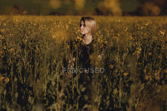 Ritratto di una bella giovane donna con in campagna distogliendo lo sguardo tra i fiori — Foto stock