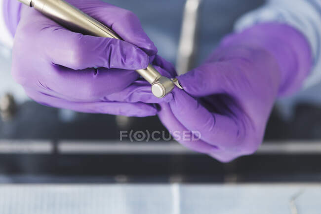 Odontólogo de cultivos en guantes que trabajan con la máquina de perforación en la clínica dental - foto de stock