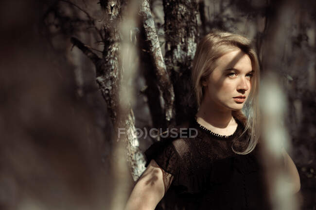 Portrait de jeune belle femme blonde dans une forêt, éclairage dramatique sur son visage — Photo de stock