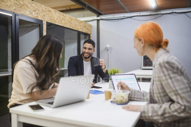 Группа сосредоточенных коллег, сидящих за столом и работающих вместе над стартап-проектом в коворкинг-пространстве — стоковое фото