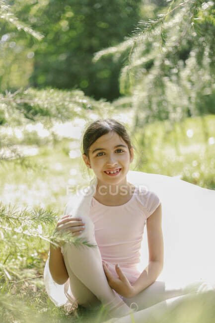 Conteúdo adolescente em vestido de balé e sapatos pontiagudos brincando com pano transparente no prado no parque no dia ensolarado — Fotografia de Stock