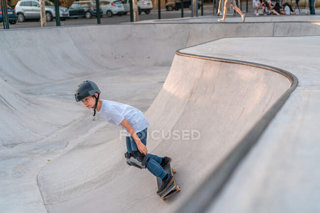 Хлопчик-підліток стрибає зі скейтбордом і показує трюк на пандусі в скейт-парку — стокове фото