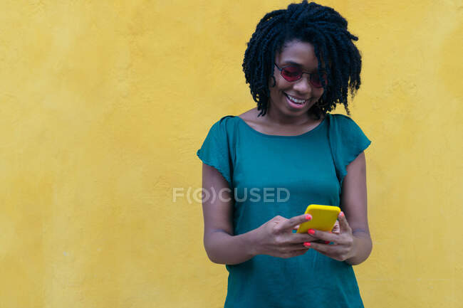 Mujer joven y feliz revisando su teléfono celular en la calle - foto de stock