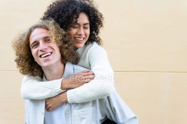 Веселий чоловік їздить верхи до різних подружки з кучерявим волоссям, сміючись голосно — стокове фото