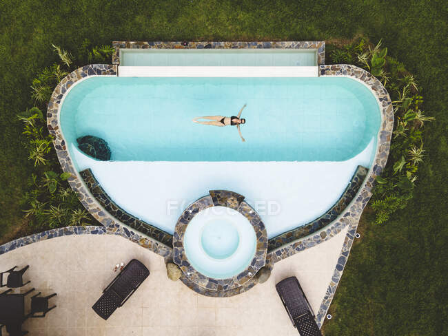 Mujer de vista superior sola en una piscina disfrutando de un día soleado de verano - foto de stock