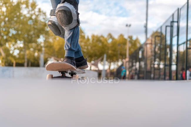 Crop adolescente skater de pie en el monopatín y la preparación para mostrar truco en la rampa en el parque de skate - foto de stock