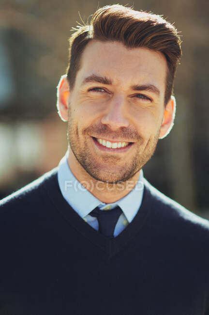 Sorrindo barbudo empresário masculino em relógio de pulso com corte de cabelo moderno olhando para longe na cidade em volta iluminado — Fotografia de Stock