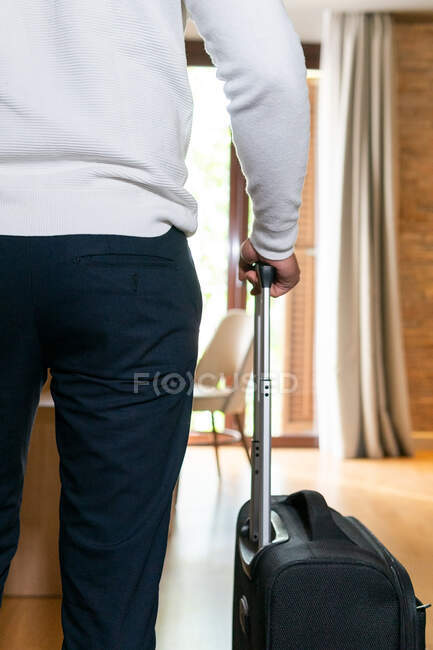 Vista trasera viajero masculino con el equipaje de pie cerca de la cama en la habitación del hotel - foto de stock