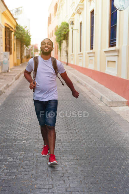 Lächelnder Mann mit Rucksack blickt nach oben, während er draußen steht — Stockfoto