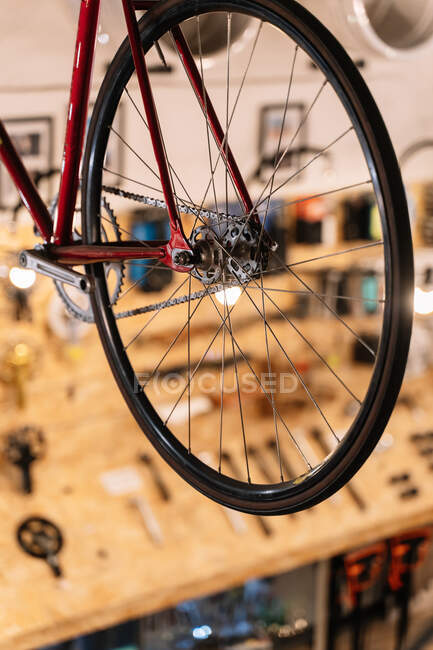 Llantas de metal brillante bicicleta colgando en estante en servicio de reparación - foto de stock