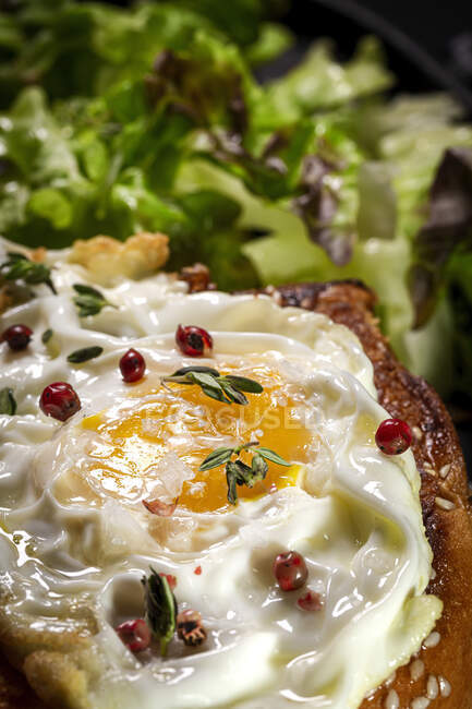 Gebratenes Ei auf Brioche serviert auf Tablett mit frischem Salat für ein appetitanregendes Frühstück auf schwarzem Hintergrund — Stockfoto