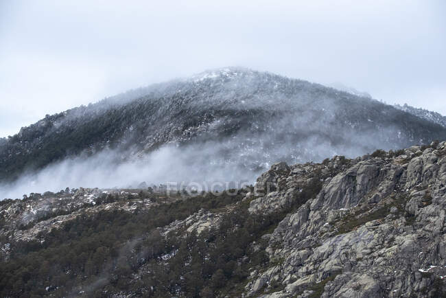 Спокойный ландшафт с горной цепью, покрытой туманом против облачного утреннего неба в Национальном парке Гуадарама в Мадриде, Испания — стоковое фото