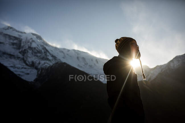 Seitenansicht eines nachdenklichen männlichen Reisenden in warmer Kleidung, der an einem sonnigen Tag in Nepal vor dem Hintergrund des Himalaya-Gebirges steht — Stockfoto