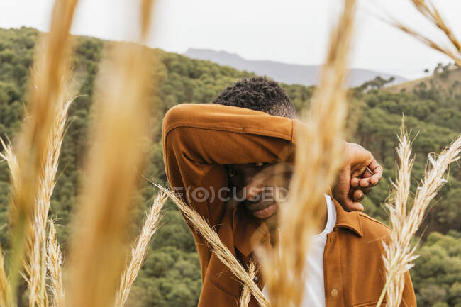 Bonito afro-americano masculino de pé em campo seco no verão e olhando para a câmera — Fotografia de Stock