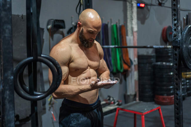 Muscular barbudo cara em sportswear espalhando pó durante o treino de musculação no ginásio — Fotografia de Stock