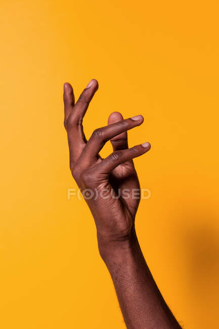 Cultivo de hombre afroamericano levantando la mano contra fondo amarillo - foto de stock