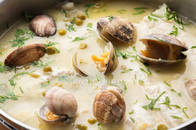 From above metal saucepan with delicious seafood soup with clams and hake — Stock Photo