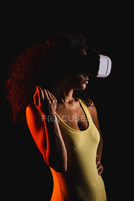 Femme anonyme ethnique explorant la réalité virtuelle dans un casque sur fond noir — Photo de stock