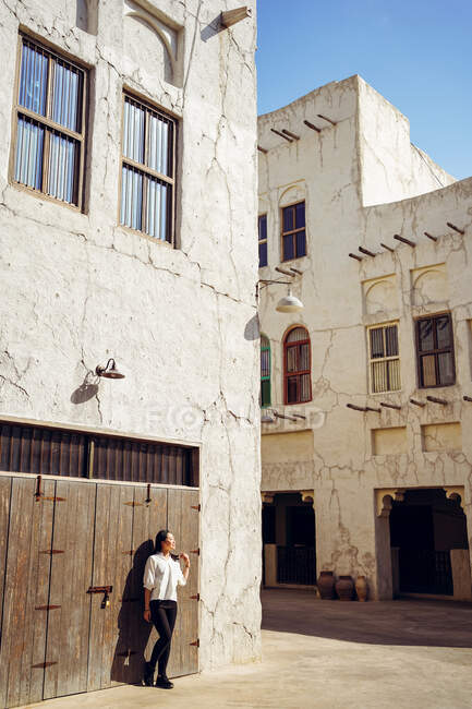Unerkennbare Reisende in Freizeitkleidung lehnen sich bei einer Besichtigungstour im historischen Viertel Al Fahidi in Dubai an verwitterte Steinbauten zurück — Stockfoto