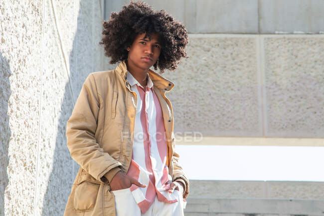 From below African American male in vintage coat with Afro hairstyle standing on stairs while looking away — Stock Photo