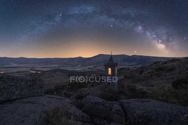 Cenário incrível com capela de pedra envelhecida em vale montanhoso sob céu noturno com Via Láctea e luz do pôr do sol — Fotografia de Stock