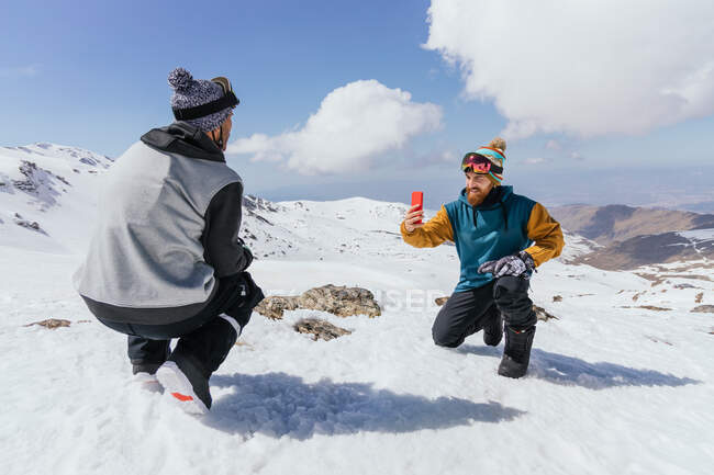 Content male friends in sports clothes taking a photo on cellphone against Sierra Nevada in wintertime — Stock Photo