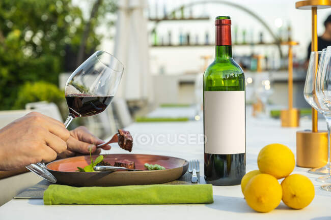 Пляшка вина і коштовностей тримає келих у ресторані високої кухні на відкритому повітрі — стокове фото
