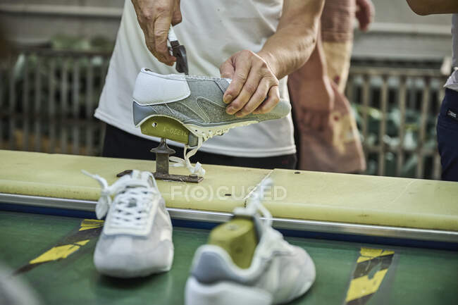 Trabajador haciendo su tarea en la línea de producción de zapatos en la fábrica de zapatos chinos - foto de stock