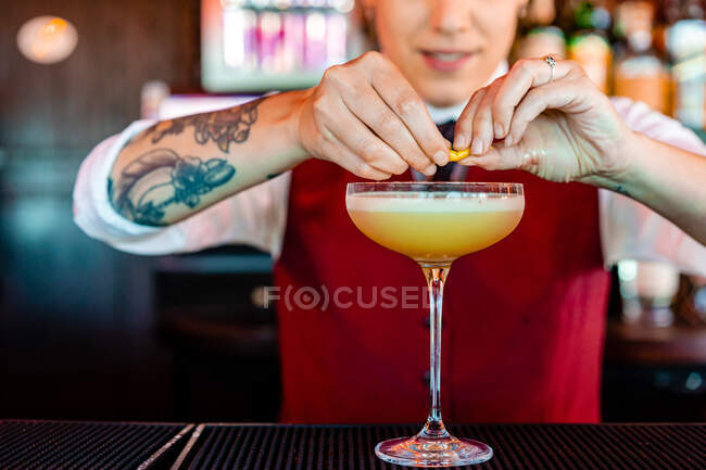 Кукурудзяний жіночий бармен прикрашає кислий коктейль у склі, поміщений на стійку в пабі — стокове фото