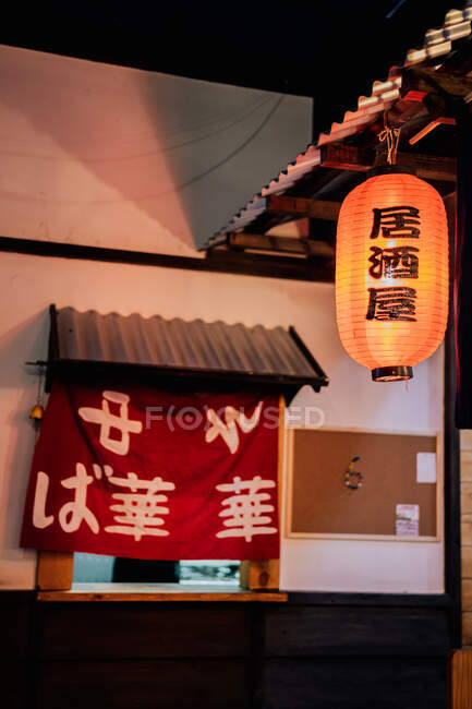 Rotes Tuch mit asiatischen Hieroglyphen im Fenster mit Metalldach eines modernen Gebäudes — Stockfoto