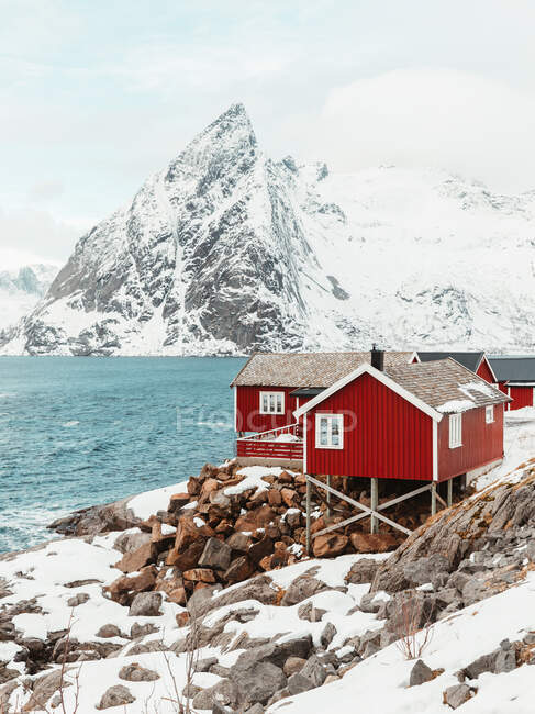 Cabanes rouges situées sur la chaîne de montagnes côte enneigée sur les îles Lofoten, Norvège — Photo de stock