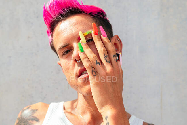Confident gay male with long colorful nails looking at camera in street on sunny day — Stock Photo