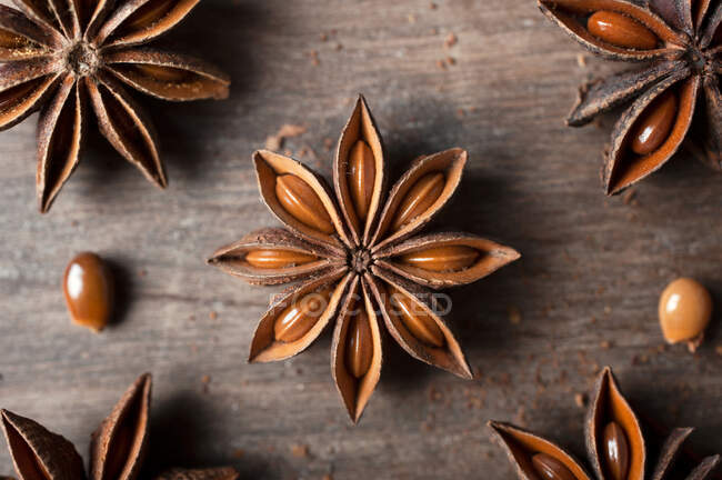 Закриття ароматичних сухих анісових зірок з насінинами, розкиданими по сільському дерев'яному столу для гастрономічного концептуального тла — стокове фото