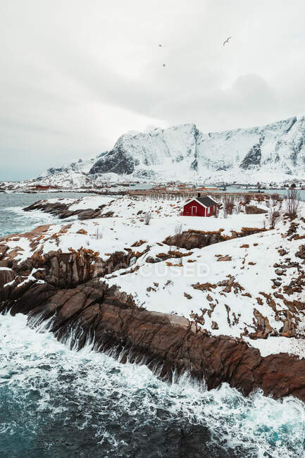 Cabine rosse situate sulla costa innevata della catena montuosa sulle isole Lofoten, Norvegia — Foto stock