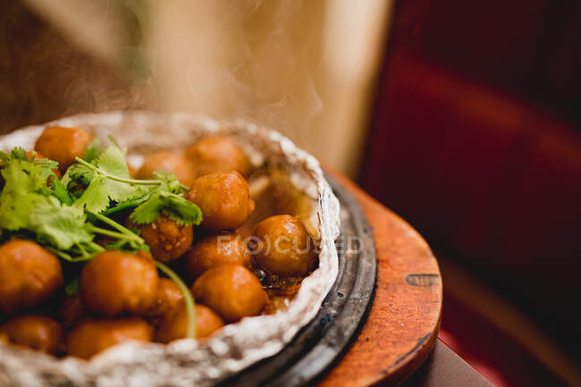 Delicious hot taro with steam fried in foil on wooden table in restaurant — Stock Photo