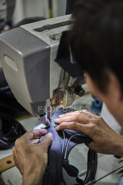 Detalle de las manos del trabajador haciendo costura en el cuero de los zapatos en la fábrica de zapatos chinos - foto de stock