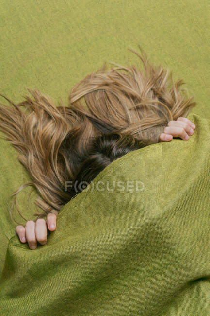 De cima de mulher anônima com rosto de cobertura de cabelo longo e claro com tecido verde — Fotografia de Stock