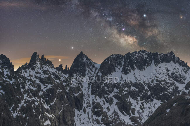 Magnificent landscape of rough rocky mountain peaks covered with snow under night starry sky with Milky Way — Stock Photo