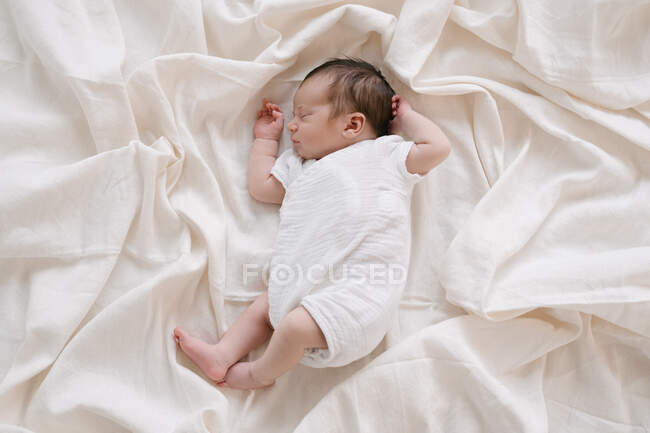 Вид сверху на сладкого младенца, лежащего на мягкой кровати и спящего дома — стоковое фото