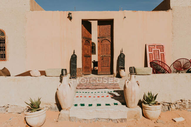 Vasos de barro e vasos com plantas colocadas perto da entrada do edifício residencial resistido no dia ensolarado em Marraquexe, Marrocos — Fotografia de Stock