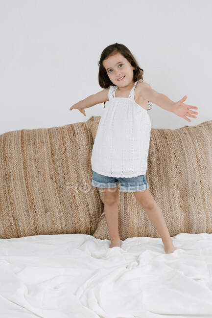 Delighted little child with outstretched arms looking at camera in living room while having fun at home — Stock Photo