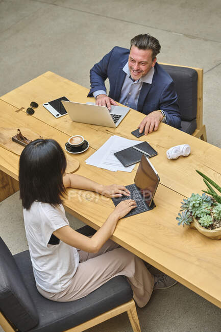 Дизайнер за своим столом, работающий за компьютером со своим ассистентом — стоковое фото