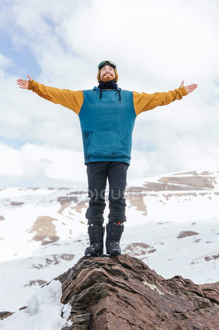 Cheerful male athlete in sports clothes looking up while standing on mount under cloudy sky in wintertime in Spain — Stock Photo