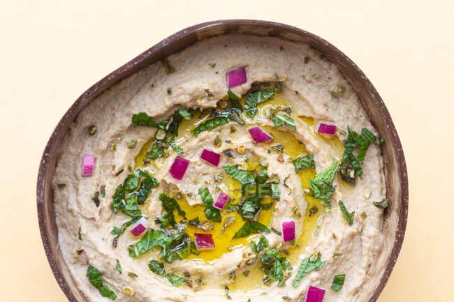 From above of appetizing traditional Baba ghanoush dish made of eggplants and garnished with herbs served in bowl on beige background — Stock Photo