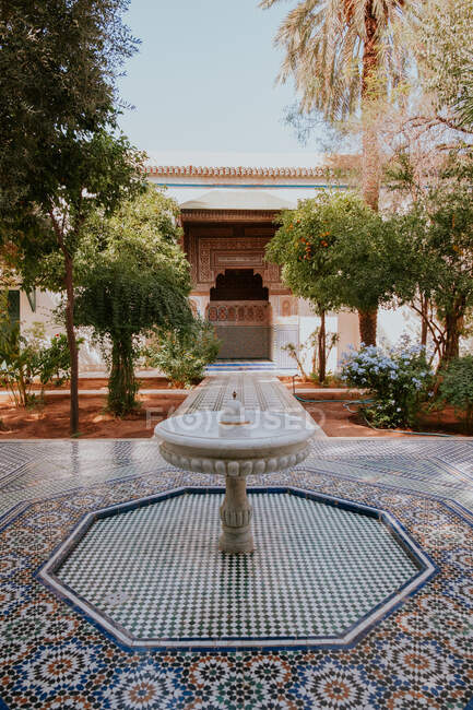 Fonte de mármore instalado no piso de mármore no meio de belo pátio do autêntico edifício islâmico no dia ensolarado em Marraquexe, Marrocos — Fotografia de Stock