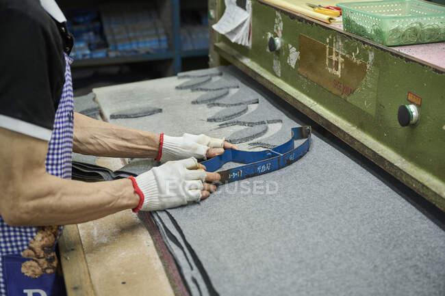Detail of worker using of cutting pattern while cutting fabric in Chinese shoes factory — Stock Photo