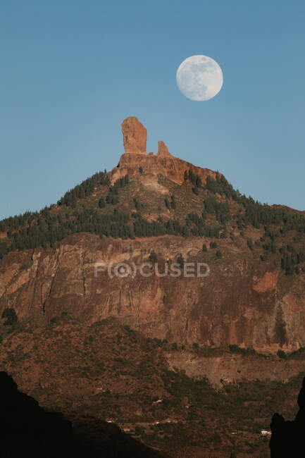 Paisagem espetacular com grande lua cheia no céu azul sobre o pico da montanha rochosa com floresta verde na noite de verão — Fotografia de Stock