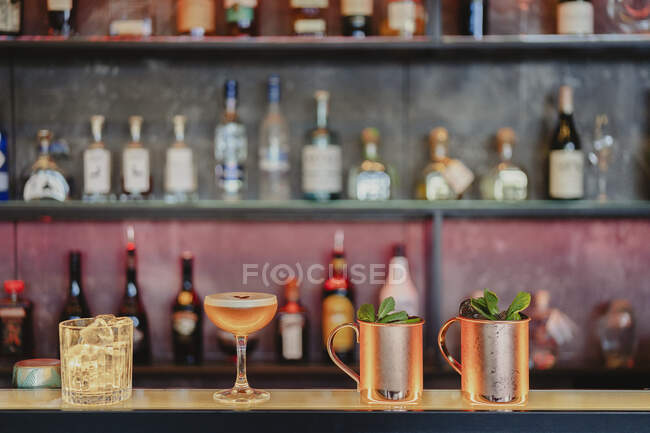 Moscow mule and sour cocktails served with glass with ice cubes on counter in bar — Stock Photo