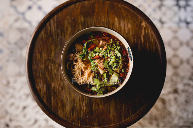 Вид сверху на чашу традиционного горячего аппетитного пряного рамена на деревянном столе в азиатском ресторане — стоковое фото